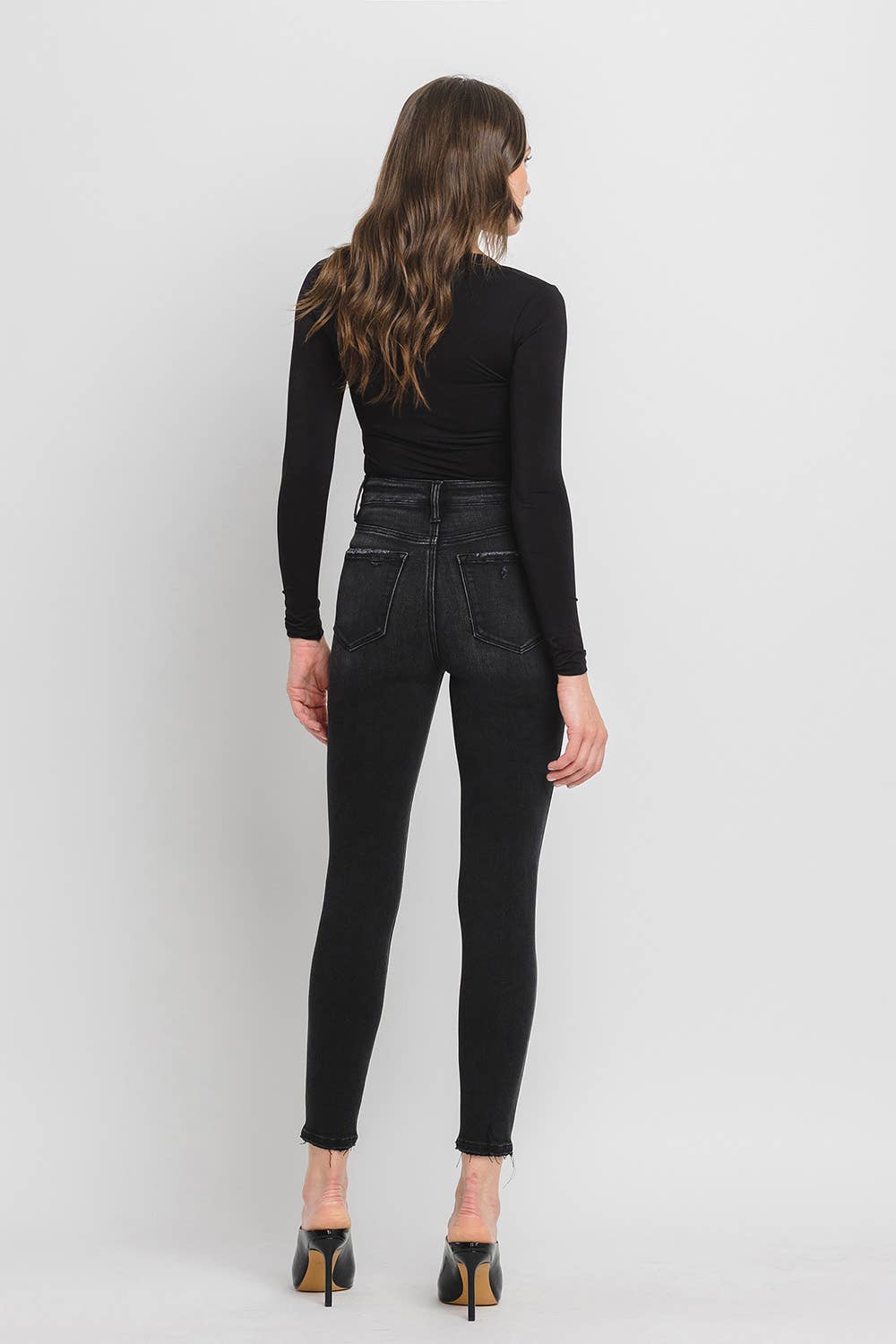 Woman wearing black jeans and a black top on a white background