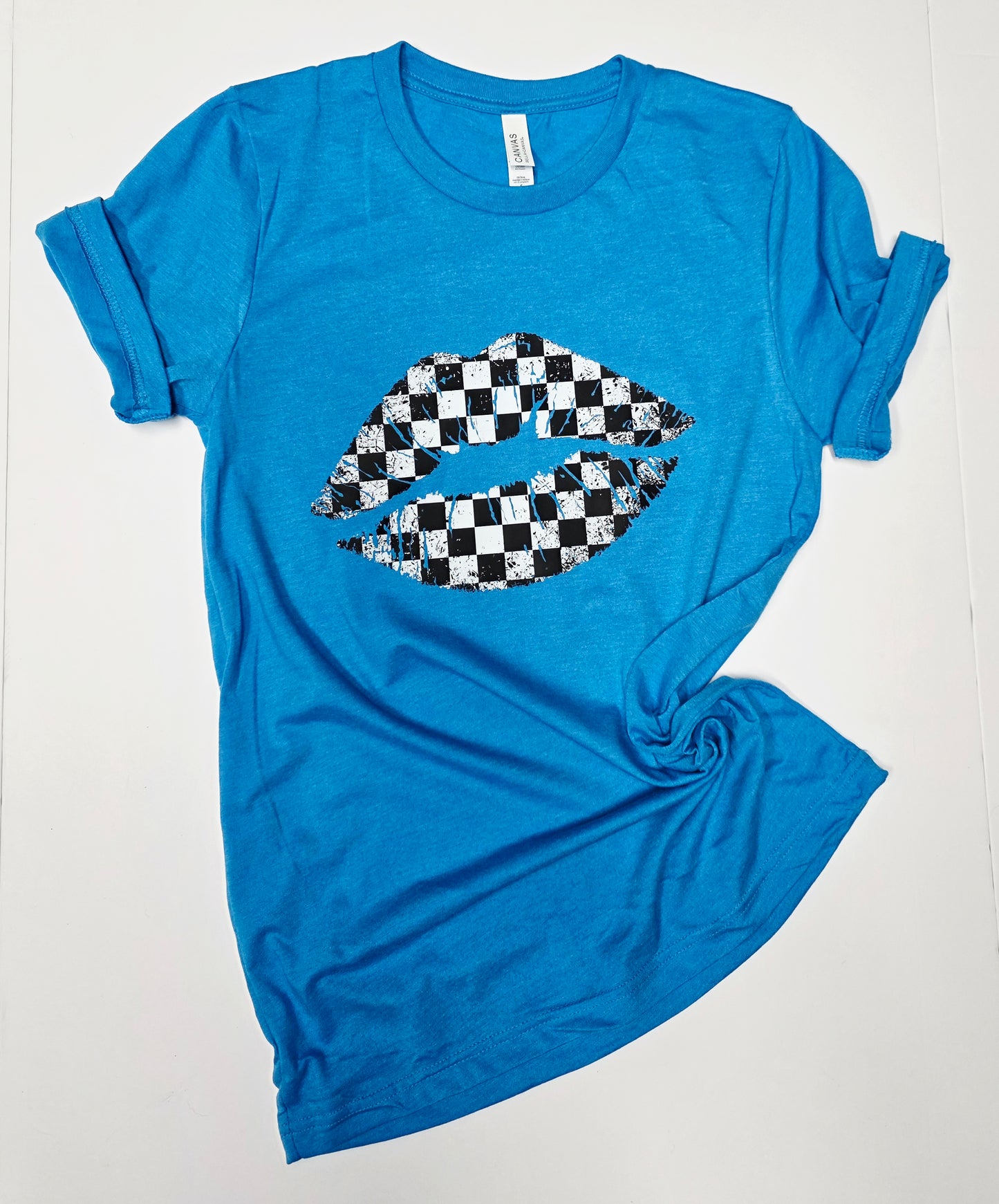 flat lay of blue graphic tee with black and white checkered graphic lips