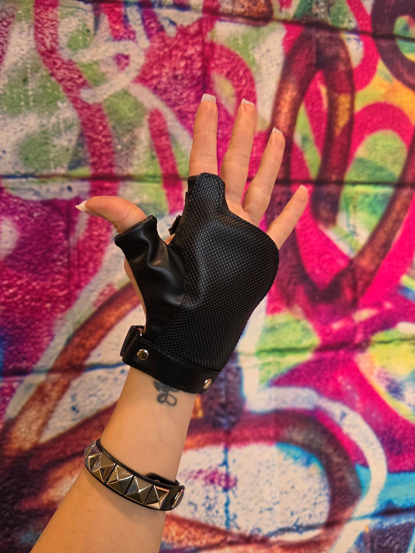 Hand wearing a black disability glove with a colorful graffiti background
