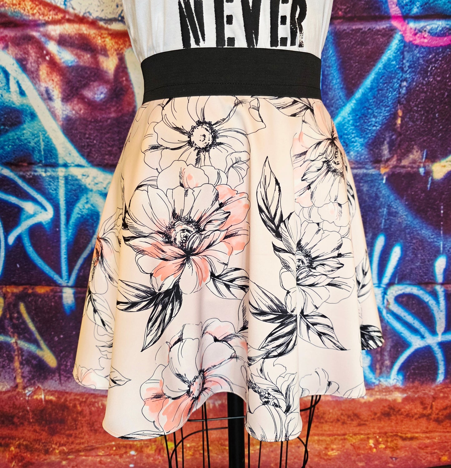 Skirt with floral pattern on a mannequin against a graffiti-covered wall.