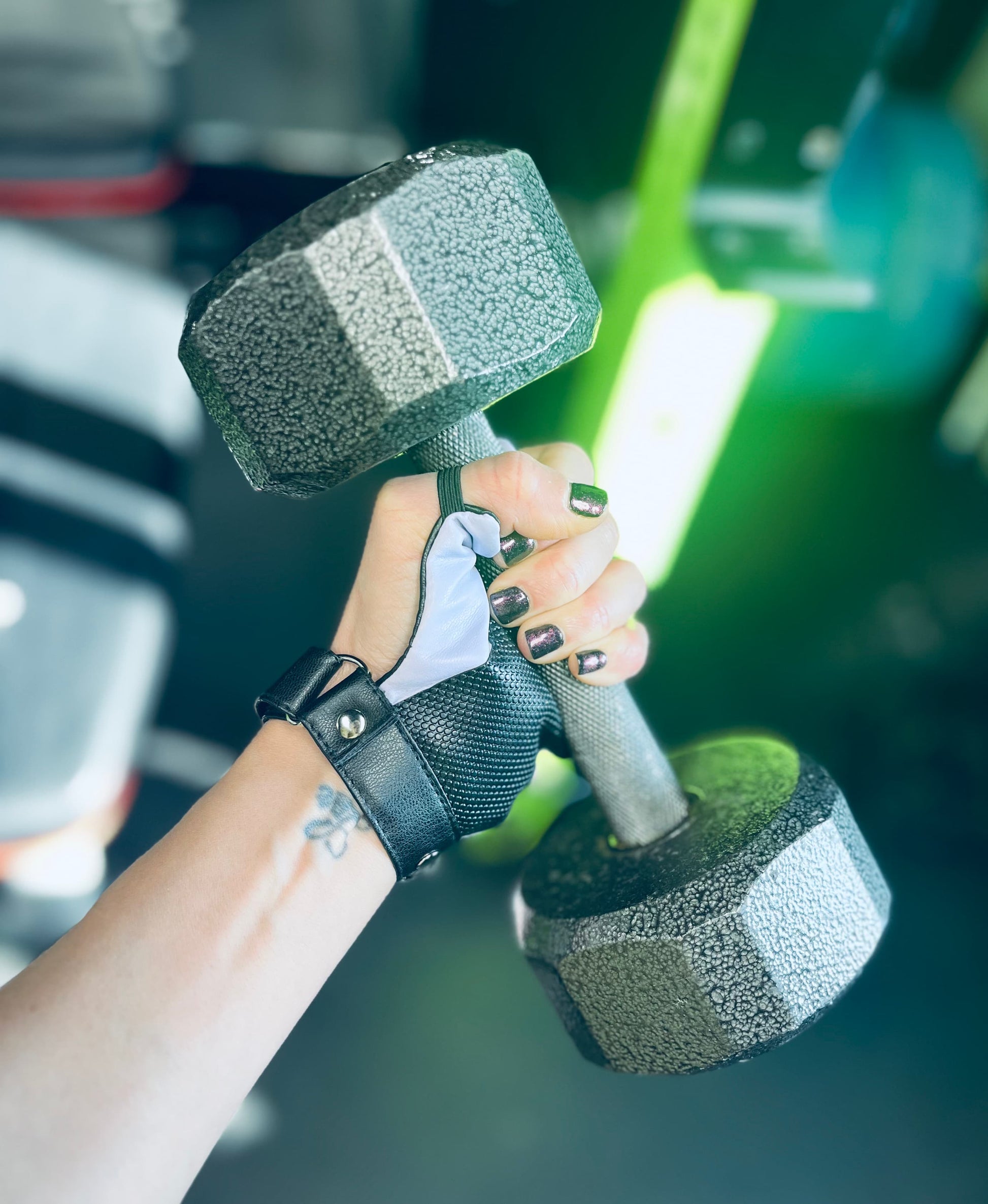 Hand with disability glove holding a dumbbell with a blurred gym background