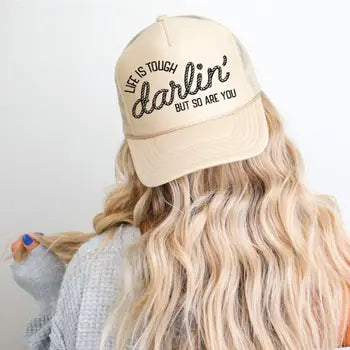 Person wearing a beige cap with text, against a plain background