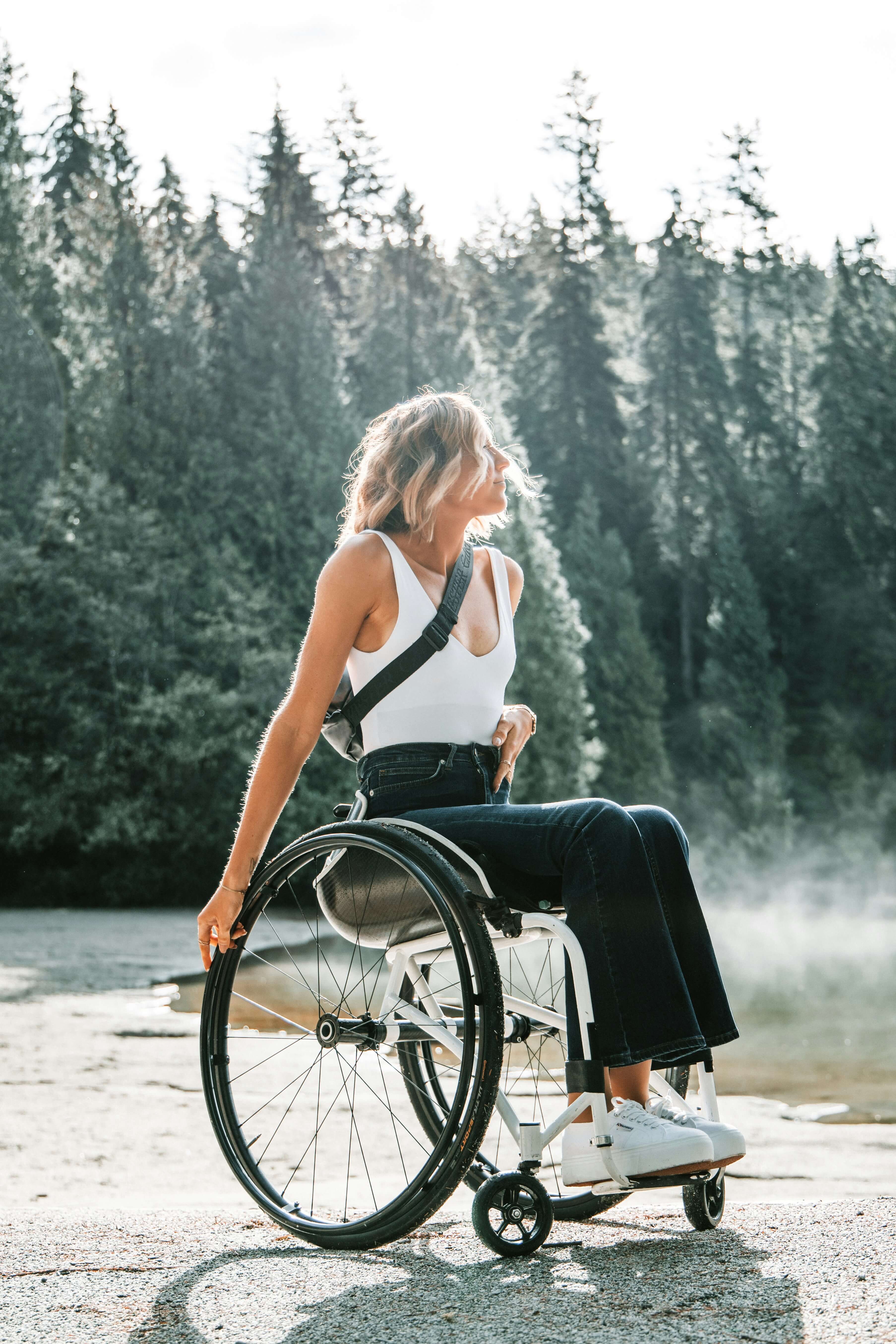 Person in a wheelchair by a lake with trees in the background